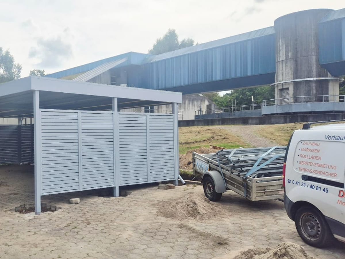 Carport mit Lamellen-Sichtschutzwand auf einem Firmengelände