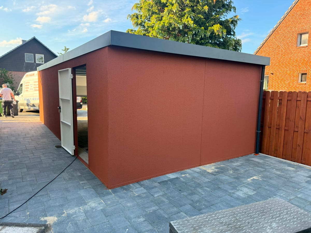 Garage in Terracotta mit Sektionaltor und gepflasterter Einfahrt