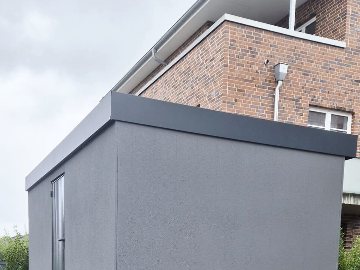 Graues Gerätehaus mit Flachdach in einer Neubausiedlung