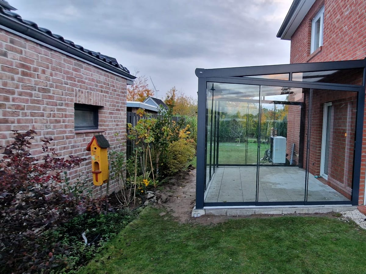Terrassenüberdachung aus Aluminium und Glas an einem Klinkerhaus, montiert von H&M Montageservice