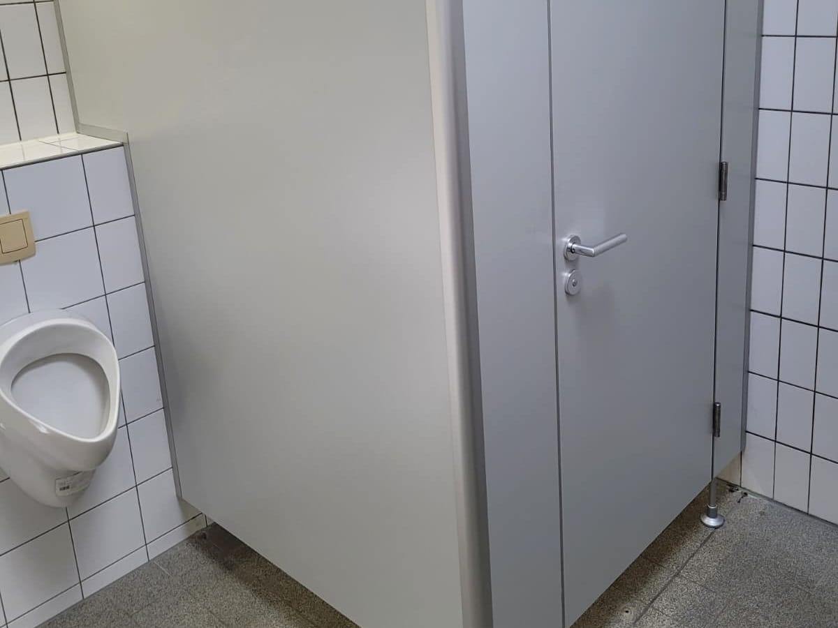 Sanitär-Trennwand mit Tür in einem gefliesten Waschraum